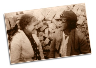 Sepia photo of two 1930s ladies smiling and chatting
